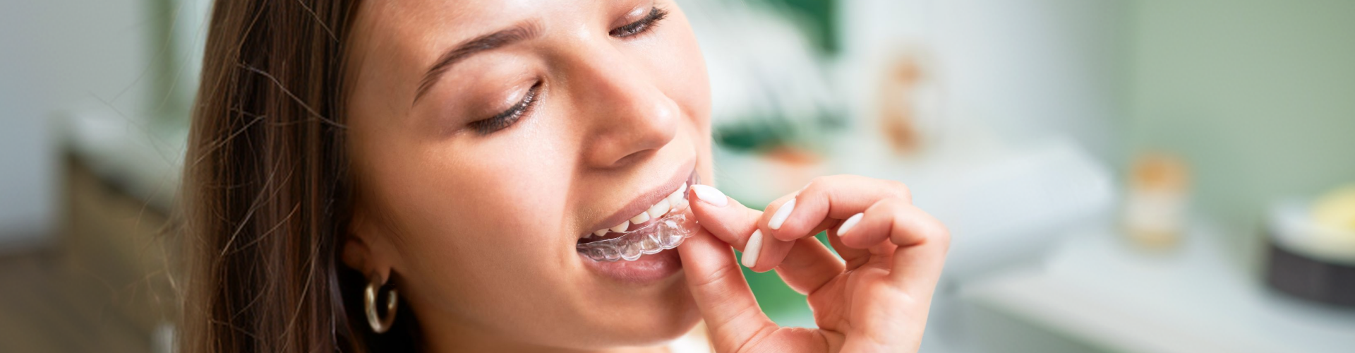 Person placing a clear Invisalign aligner onto their teeth, demonstrating how removable clear aligners provide a discreet and comfortable way to straighten teeth.
